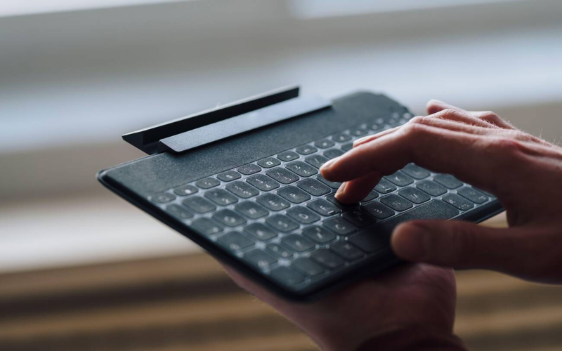 A person holding a wireless keyboard